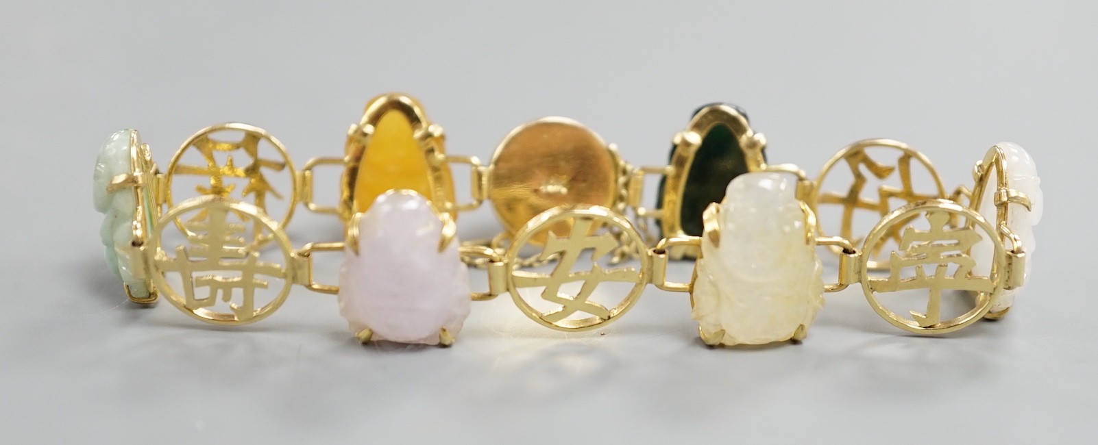 A Chinese 14k yellow metal and hardstone set bracelet, with alternating character and six carved Buddha set links, approx. 17cm, gross weight 17.3 grams.